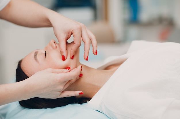 Young woman getting face treatment massage at beauty spa salon