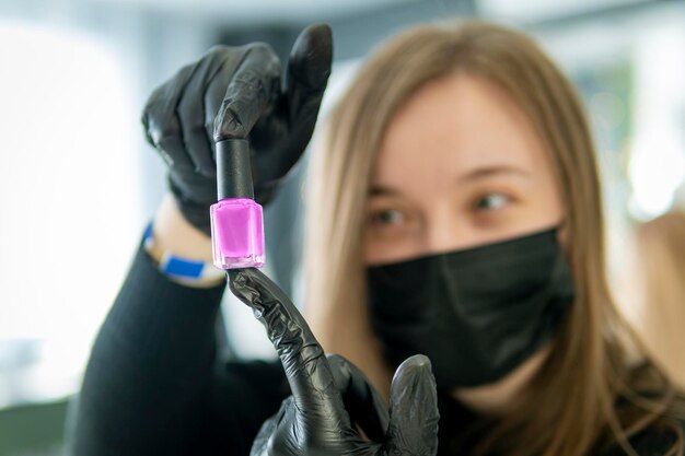 Молодая женщина получает ногти от маникюриста в салоне красоты бутылка лака для ногтей