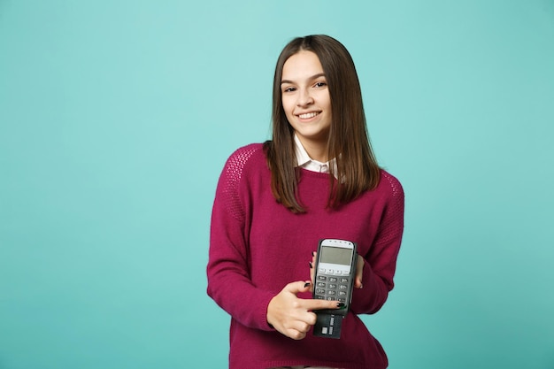 Young woman girl in casual clothes isolated on blue background studio portrait. People lifestyle concept Mock up copy space. hold in hand wireless bank terminal to process acquire credit card payments