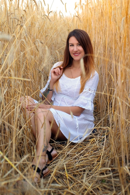 a young woman or girl in a field with wheat walks at sunset