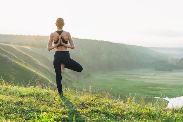 Young woman girl practice yoga looking on the beautiful landscape on early morning Local tourism weekend trip