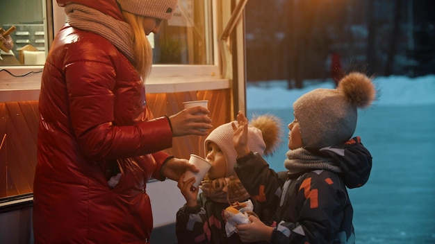 Young woman gives her children hot drinks