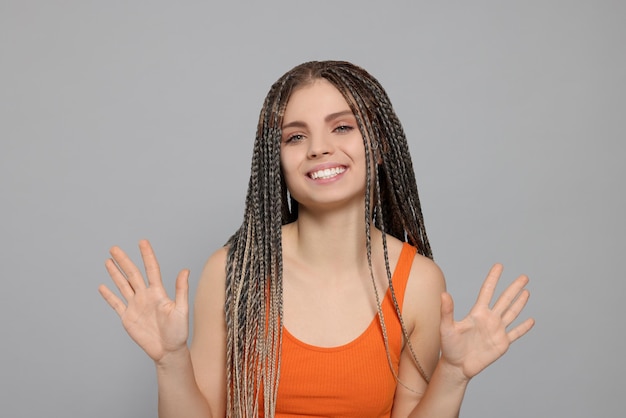 Young woman giving high five with both hands on grey background