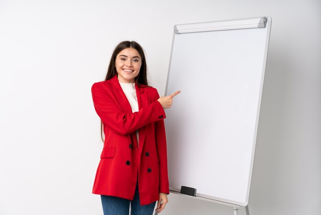 Young woman giving a presentation on white board pointing to the side to present a product