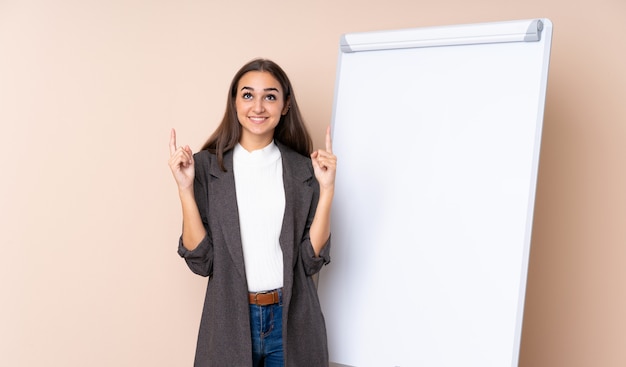 Giovane donna che dà una presentazione sul bordo bianco che indica su una grande idea