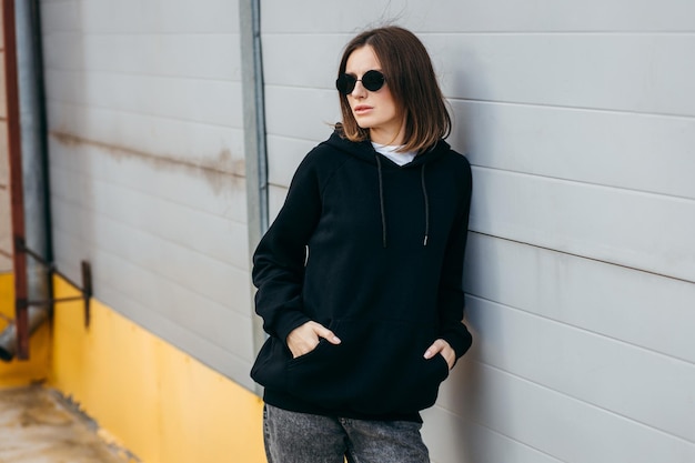 Young woman in glasses and black hoodie