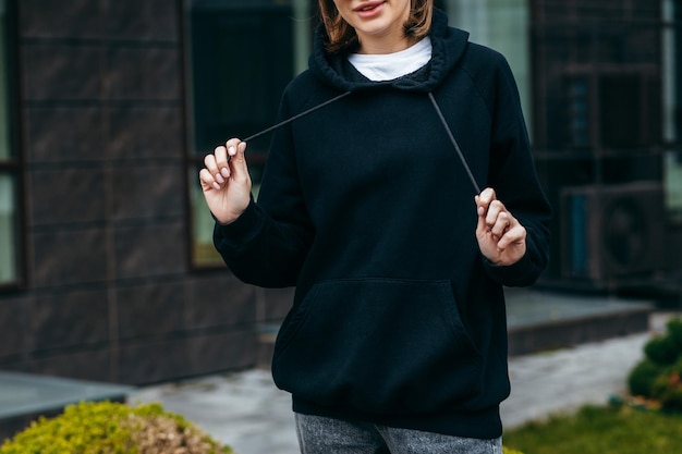 Young woman in glasses and black hoodie