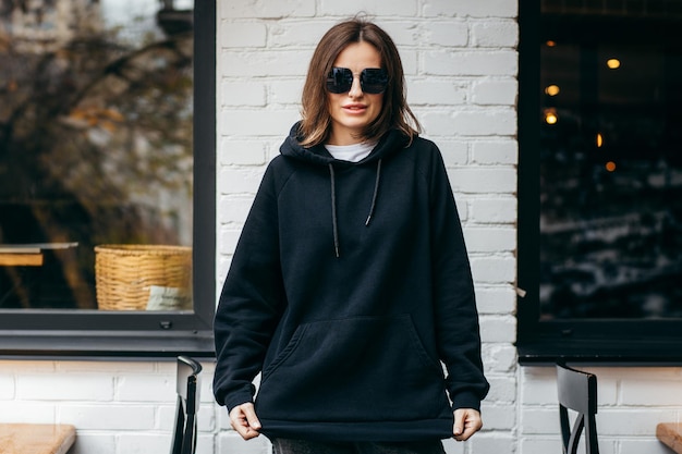 Young woman in glasses and black hoodie