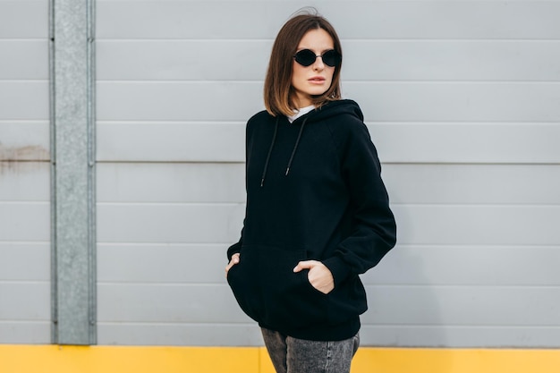 Young woman in glasses and black hoodie