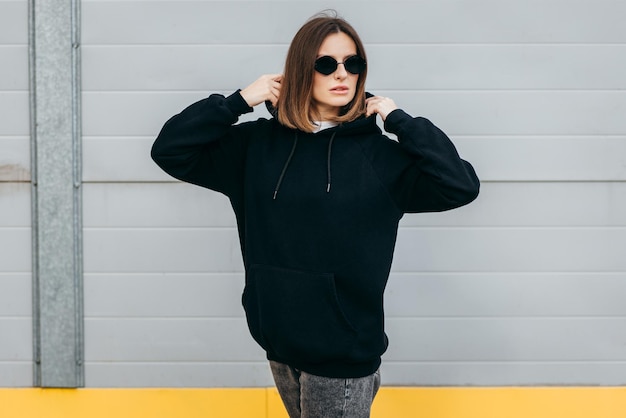 Young woman in glasses and black hoodie