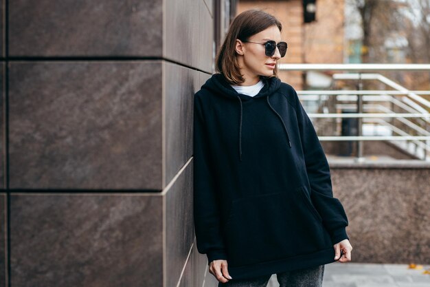 Young woman in glasses and black hoodie