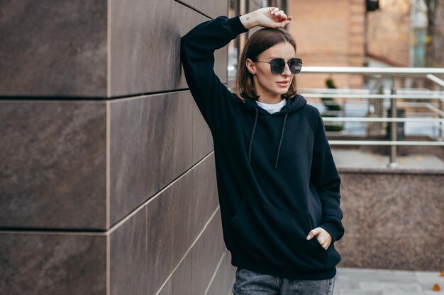 Young woman in glasses and black hoodie