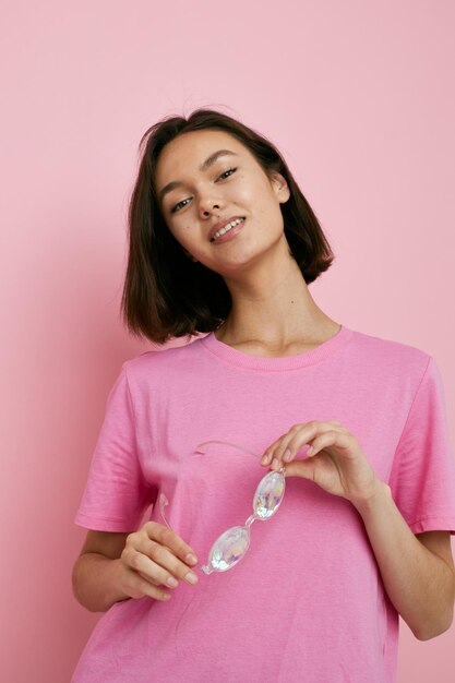 Очки молодой женщины в виде бриллиантов на розовом фоне футболки розового цвета