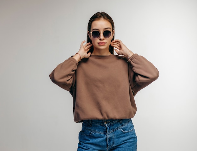 Young woman in glasses and hoodie posing 