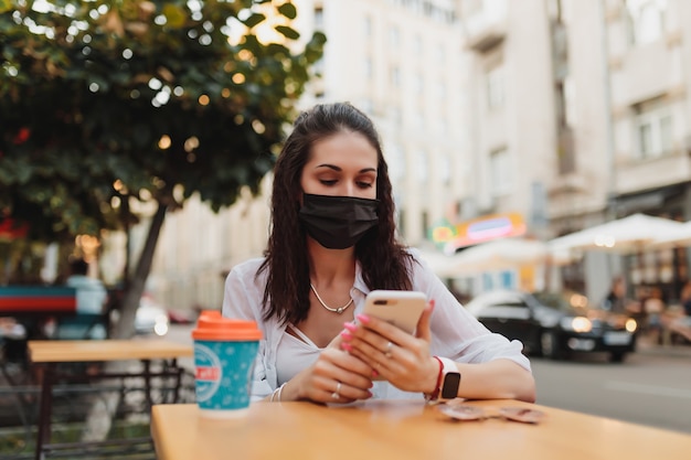 Giovane donna in occhiali e maschera utilizza il telefono. foto di alta qualità