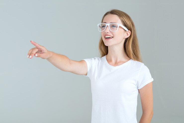 メガネの若い女性が灰色に分離された側に指を指す