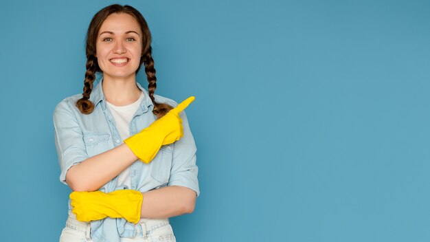 Giovane donna in guanti per la pulizia su uno sfondo blu isolato