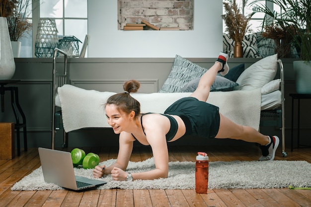 Photo young woman goes in for sports at home, training online