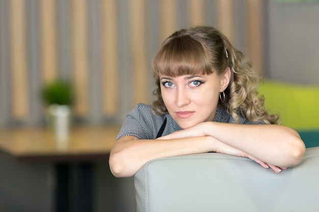 A young woman in a gray dress is sitting in a trendy cafe.