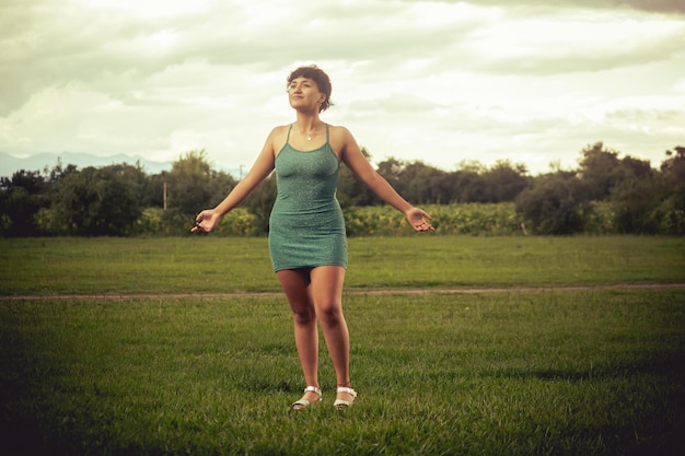 Young woman in green dress posing in nature