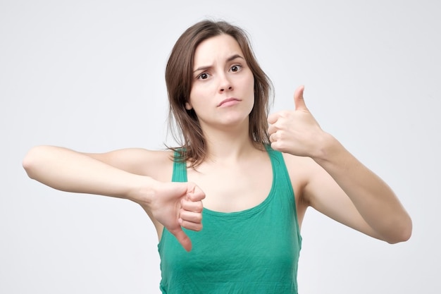 Young woman in green tshirt showing thumbs up and down sign