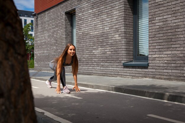 暖かい夏の日に街でストレッチを行うスポーツウエアでスリムな体型の若い女性の体操選手。戸外でのストレッチ