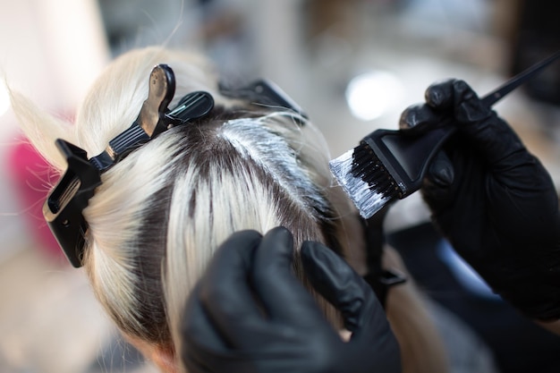 美容院で髪を染める若い女性美容師 プロの髪の根の着色