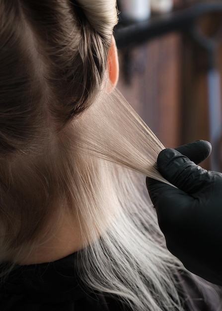 Young woman in a hairdressing salon dyes her hair blond