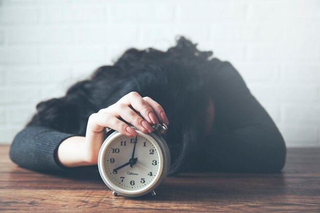 Young woman hand clock on table