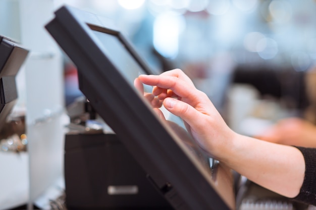 young woman hand doing process payment on a touchscreen cash register, finance concept