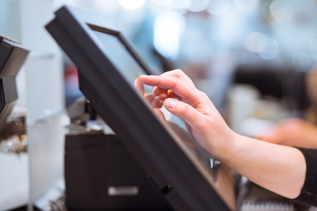 Young woman hand doing process payment on a touchscreen cash register, finance concept