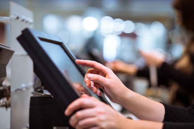 Young woman hand doing process payment on a touchscreen cash register, finance concept