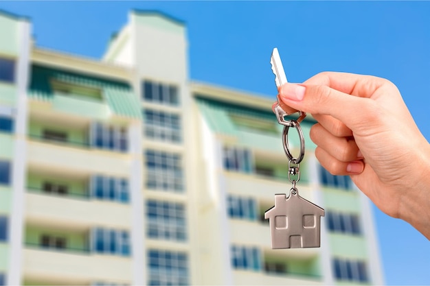 Young woman hand holding key on building background