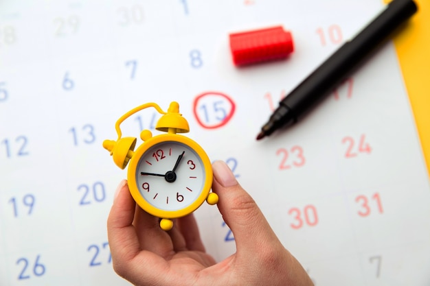 Young woman hand holding yellow clock.