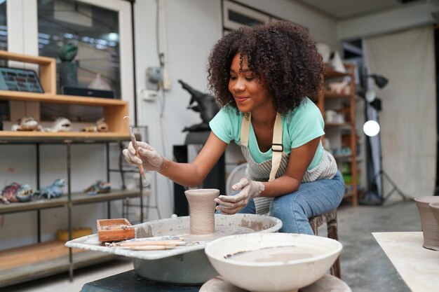 Young woman hand potter making clay vase in pottery workshop\
business owner