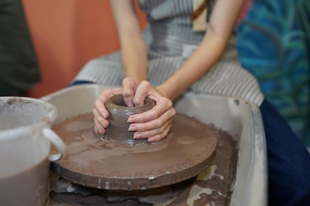 Young woman hand potter making clay vase in pottery workshop\
business owner