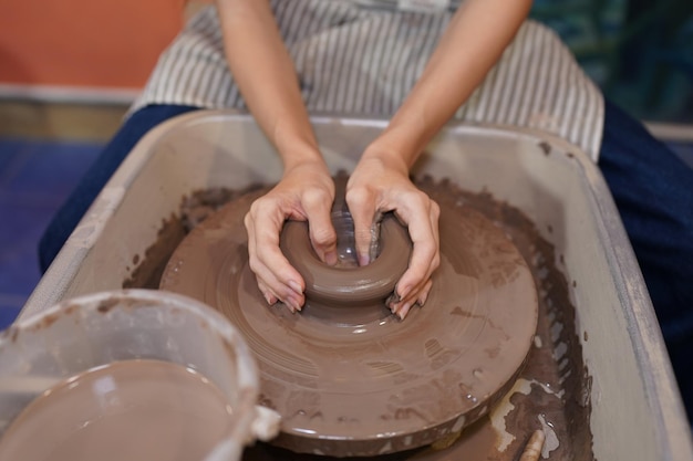 Young woman hand potter making clay vase in pottery workshop\
business owner