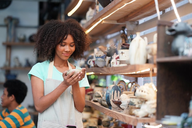 Young woman hand potter making clay vase in pottery workshop\
business owner