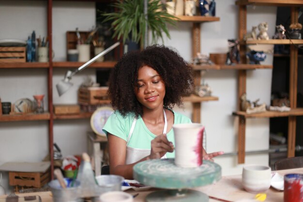 Young woman hand potter making clay vase in pottery workshop\
business owner