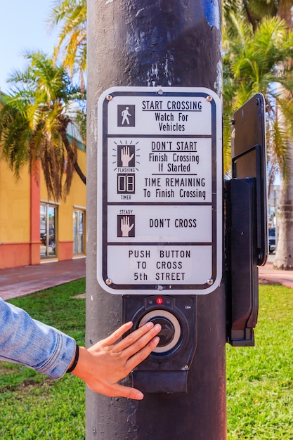 Young woman hand pushing button for traffic light. Use traffic lights at the crossroads. 