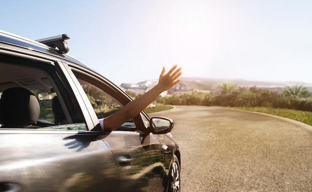 Young woman hand waving from car window copy space