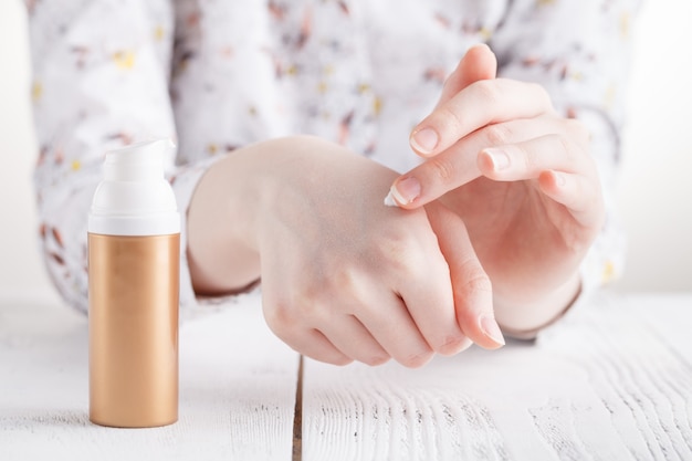 Young woman hands applying moisturizing cream to her skin