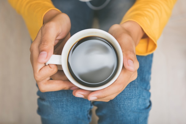 Young woman hands holding cup of hot black coffee 