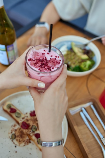 Young woman hands holding freshly squeezed strawberry lemonade of citrus fruits Female with mason jar full of cold cocktail lemon orange lime mint leaves