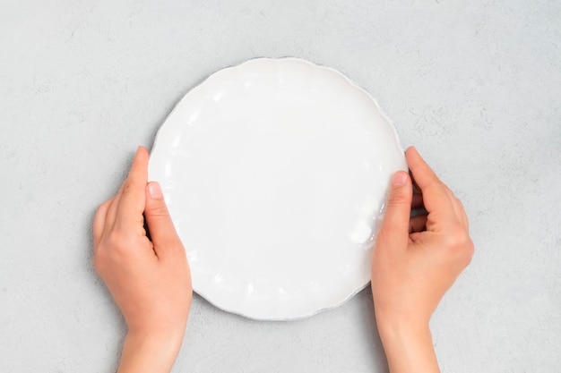 Young woman hands holding white empty plate