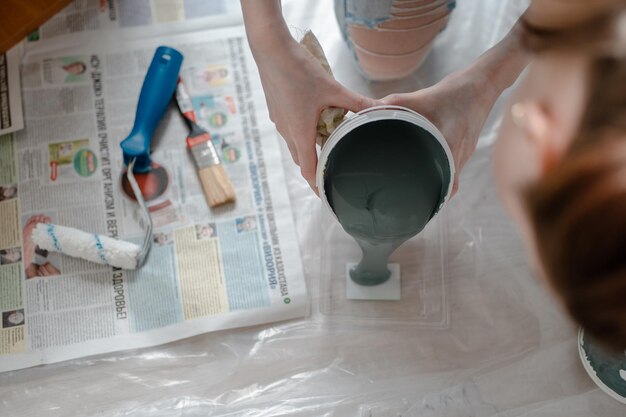 Young woman hands pouring paint into tray