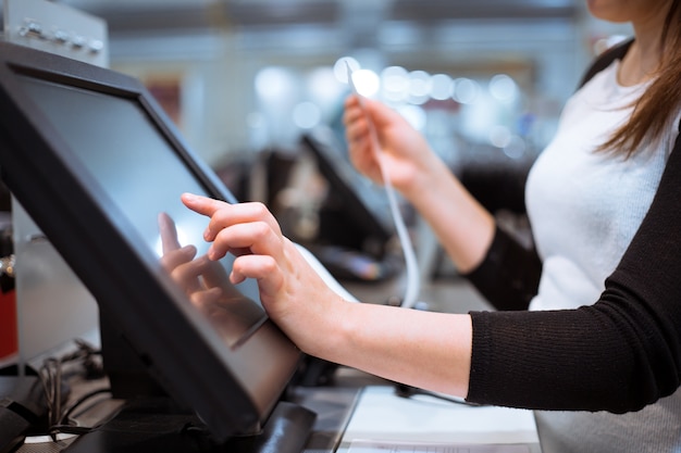 Photo young woman hands scaning / entering discount / sale on a receipt, touchscreen cash register, market / shop