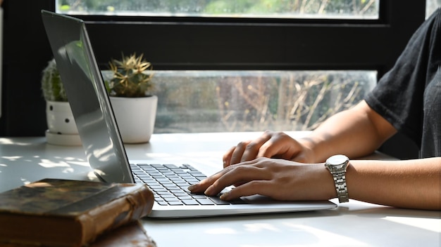 Young woman hands typing on computer laptop while sitting in bright home office