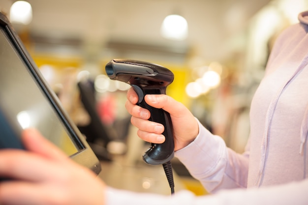 Young woman hands using scanner for scanning goods for a customer at huge shopping center