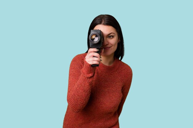 若い女性が孤立した背景にアンティークのビデオ カメラで楽しそうに撮影しています。